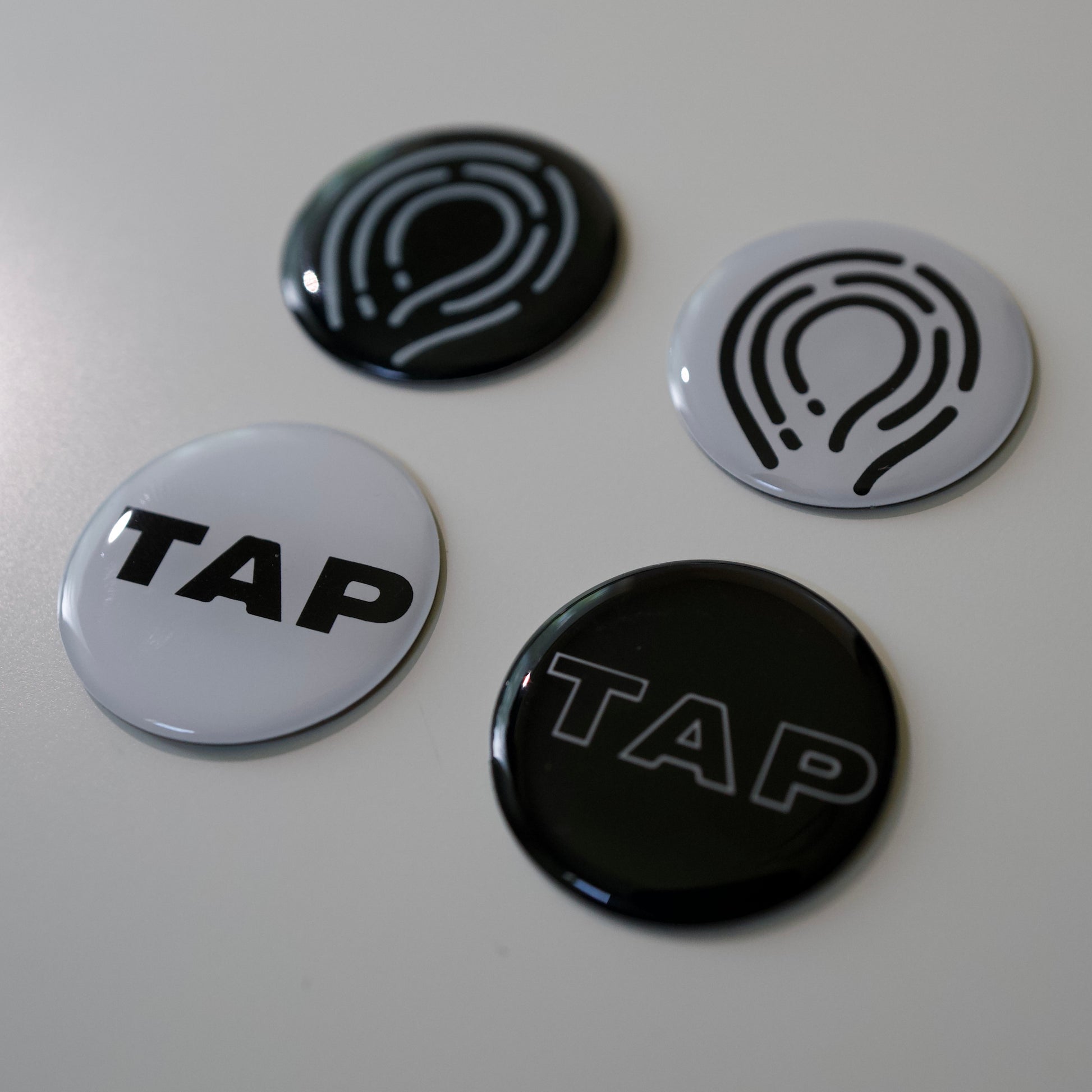 Four black and white NFC tags displayed side by side, each designed for easy programming and integration with smart devices for versatile applications.