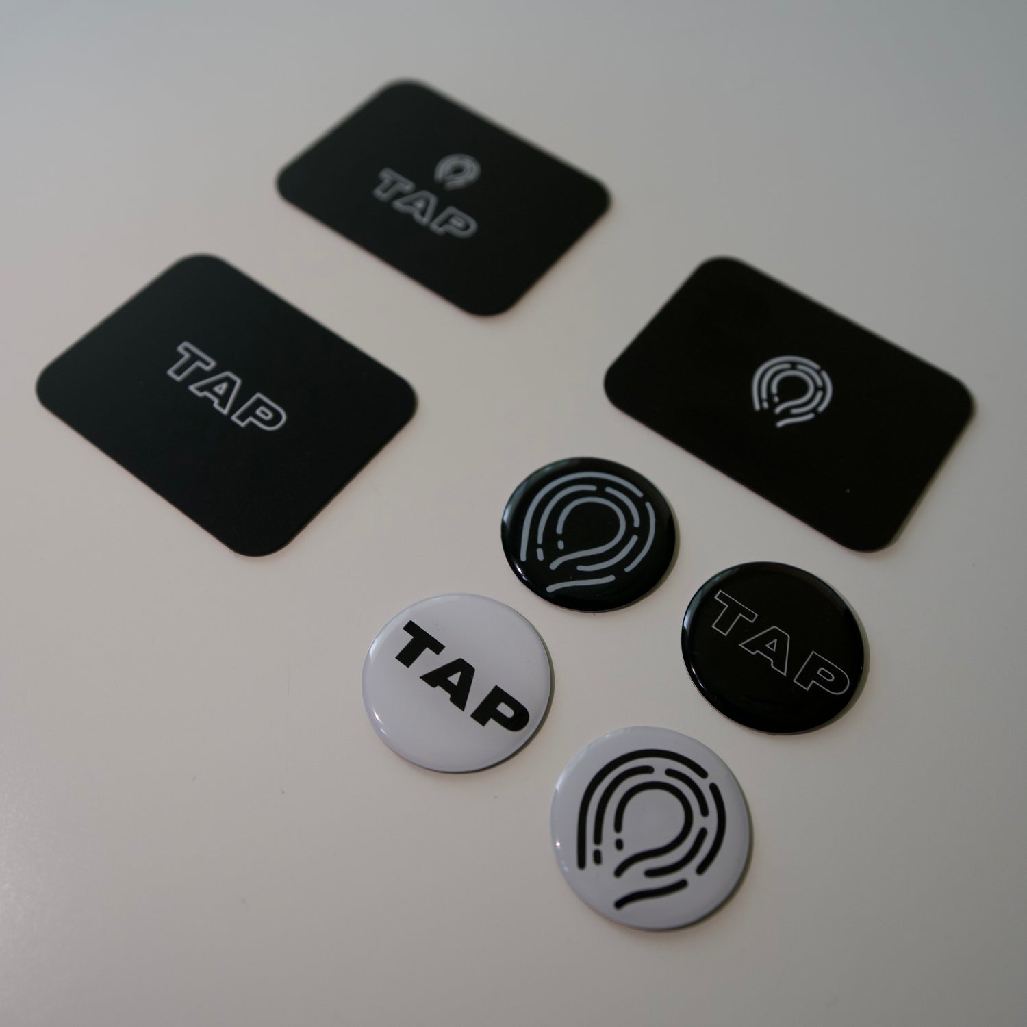 Black and white photo of four NFC tags alongside three NFC business cards, showcasing minimalist design and modern connectivity solutions.