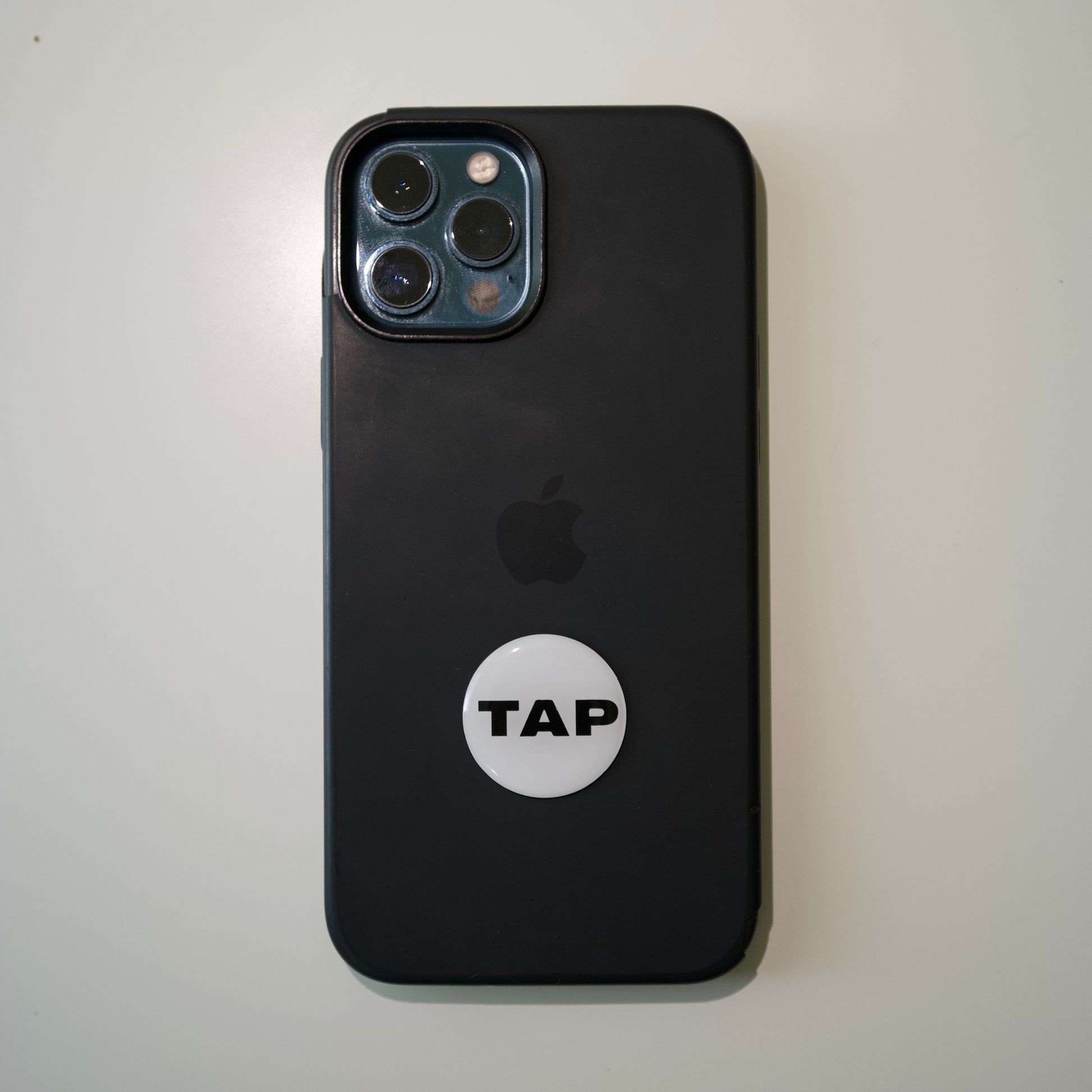 Tap Networking NFC business tag attached to the back of an iPhone, demonstrating seamless integration with mobile technology for effortless contact sharing