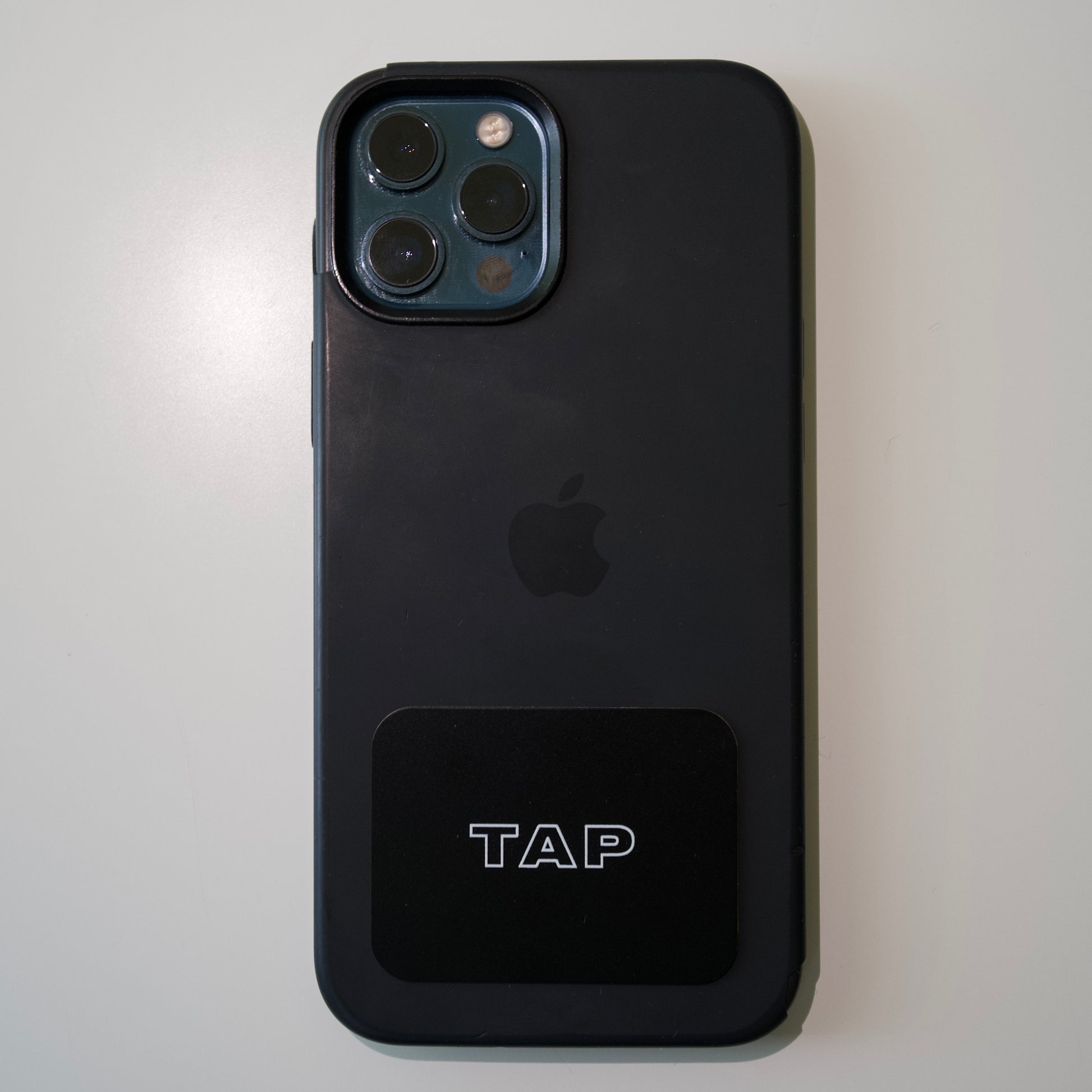 Tap Networking NFC business card attached to the back of an iPhone, demonstrating seamless integration with mobile technology for effortless contact sharing